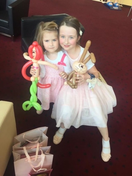 Glückliche Mädchen mit Ballonfiguren beim Kindergeburtstag